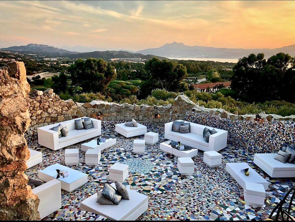 Divani bianchi e pouf su terrazza a mosaico al tramonto