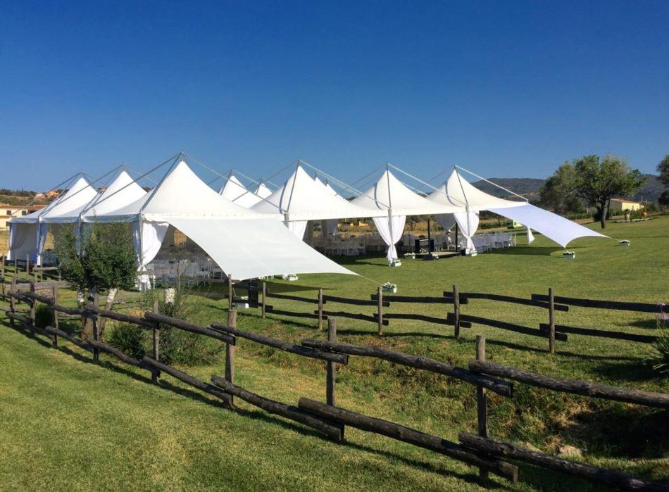 Fila di gazebo bianchi con vele su un prato collinare